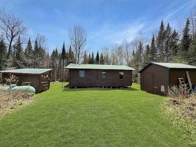 back of house with a lawn, an outdoor structure, and metal roof
