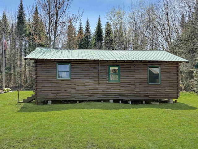 view of side of property featuring log siding, a lawn, and metal roof