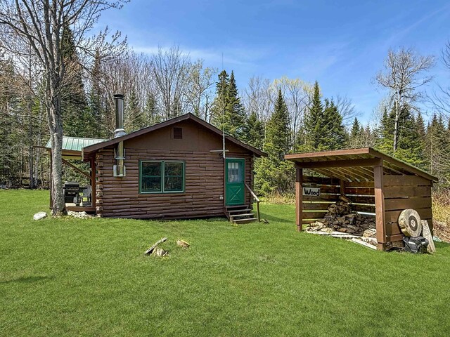 back of property featuring entry steps, log siding, and a lawn