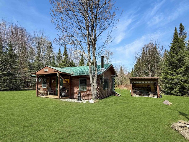 rear view of house with a lawn, metal roof, and an outbuilding
