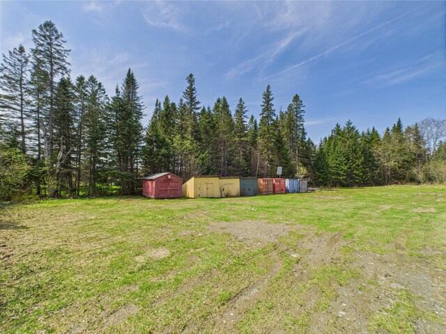 view of green lawn featuring a storage unit and an outbuilding