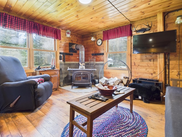 living area featuring a wood stove, wooden walls, wood ceiling, and hardwood / wood-style flooring