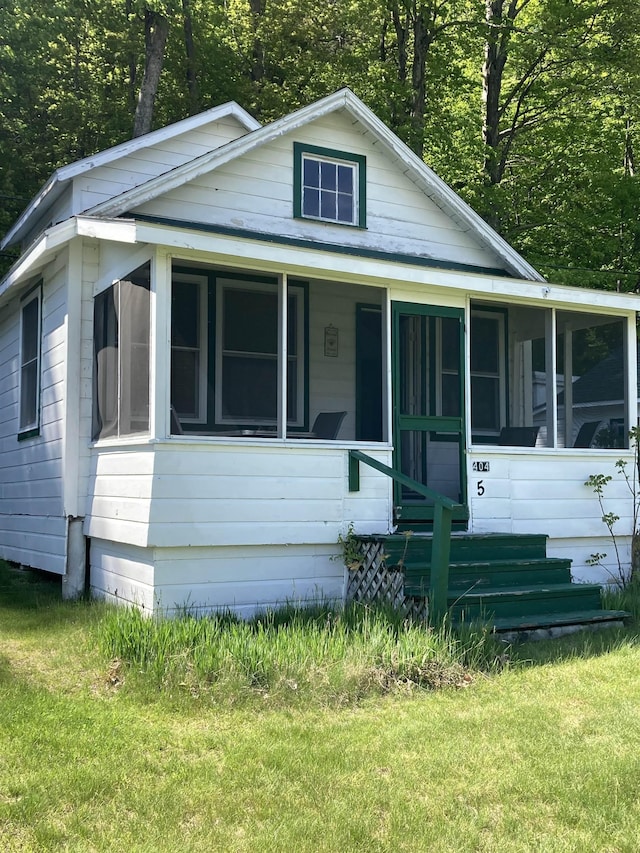 view of front of property with a sunroom and a front yard