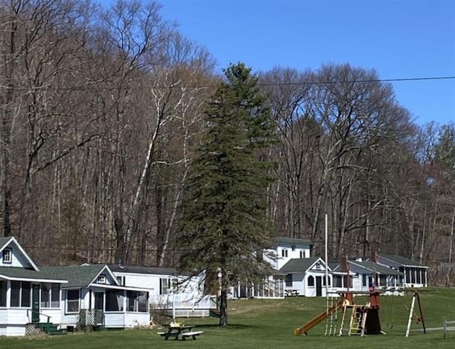 view of green lawn with a playground and a sunroom
