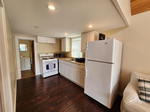 kitchen featuring white appliances, dark wood-type flooring, white cabinets, recessed lighting, and light countertops