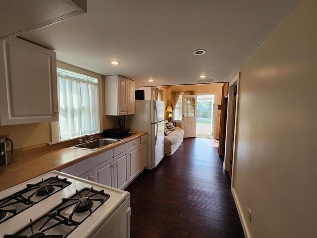 kitchen featuring a sink, white appliances, white cabinets, dark wood-style floors, and recessed lighting