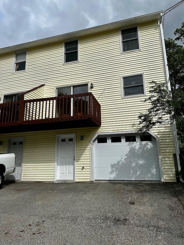 view of front of property featuring a garage, asphalt driveway, and a balcony