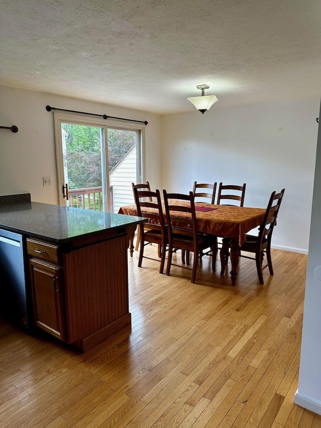 dining room featuring light wood-style floors and a textured ceiling