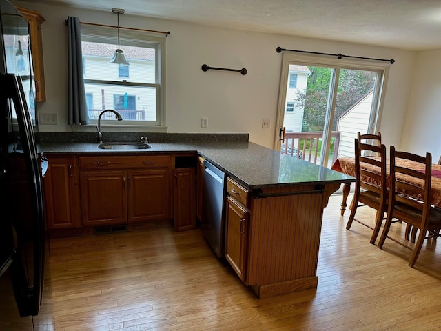 kitchen featuring a sink, stainless steel dishwasher, freestanding refrigerator, light wood-style floors, and a peninsula