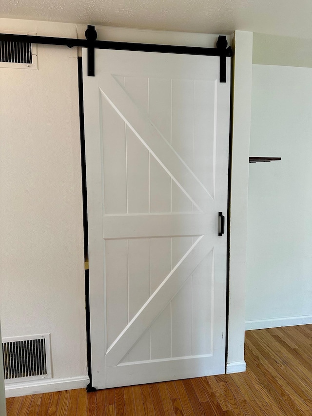 detailed view of a barn door, wood finished floors, and baseboards