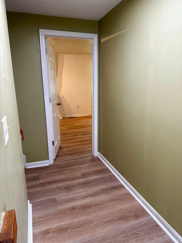 hall featuring wood finished floors and baseboards