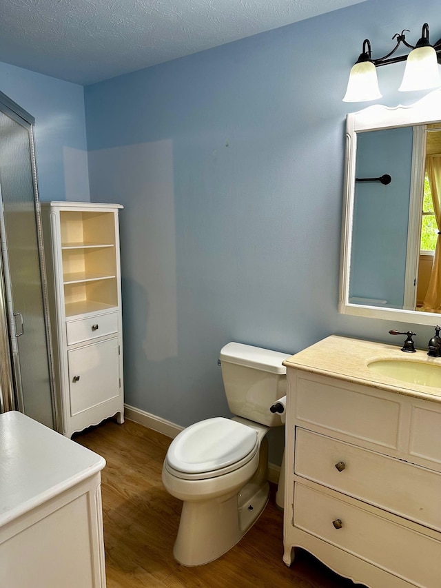 bathroom featuring wood finished floors, toilet, baseboards, and vanity