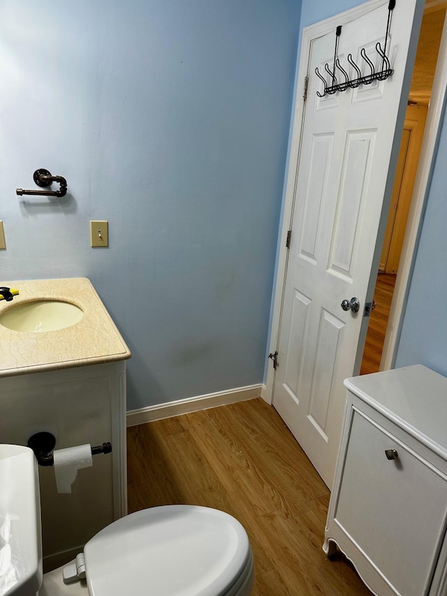 bathroom with wood finished floors, vanity, and baseboards