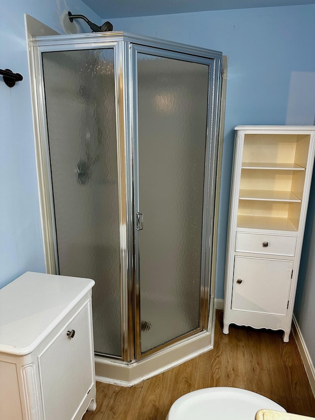 full bathroom featuring wood finished floors, a stall shower, and baseboards