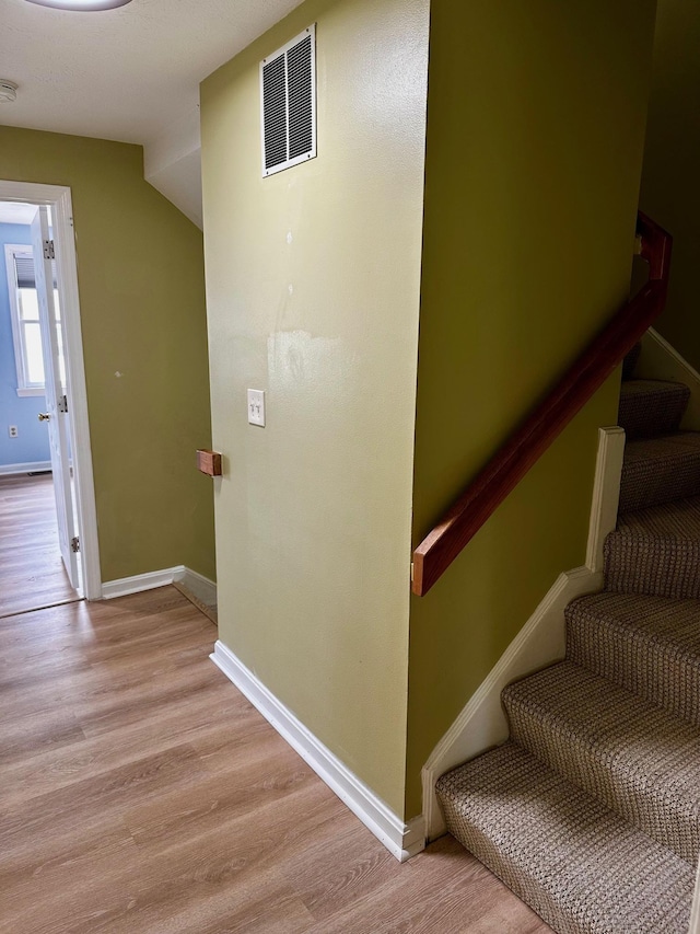 stairway with wood finished floors and baseboards