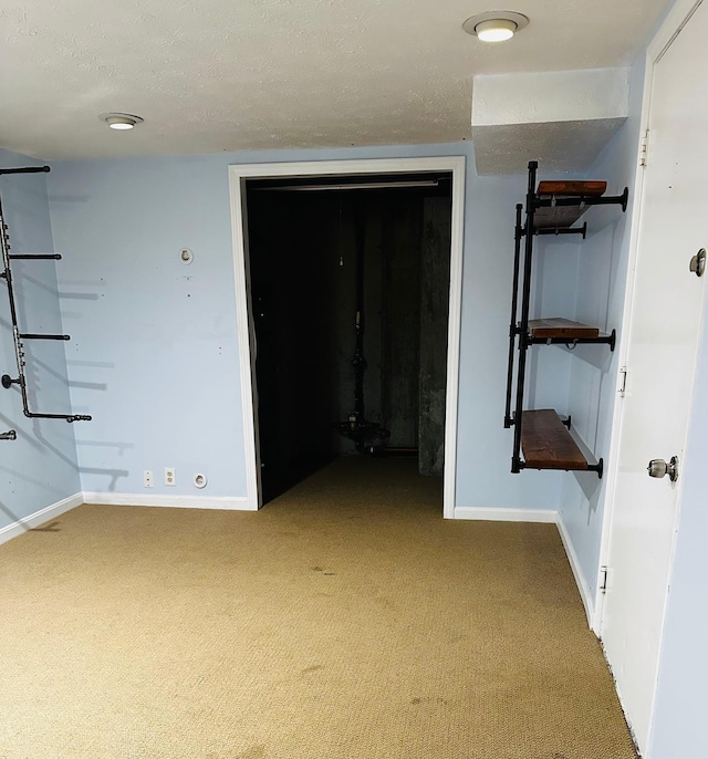 hall featuring baseboards, carpet, and a textured ceiling