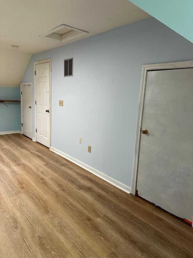 additional living space featuring wood finished floors, vaulted ceiling, and baseboards