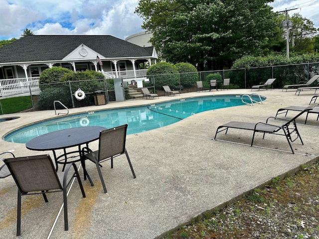 community pool with fence and a patio area