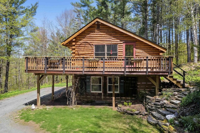 view of front of house with a deck, stairs, asphalt driveway, and log siding
