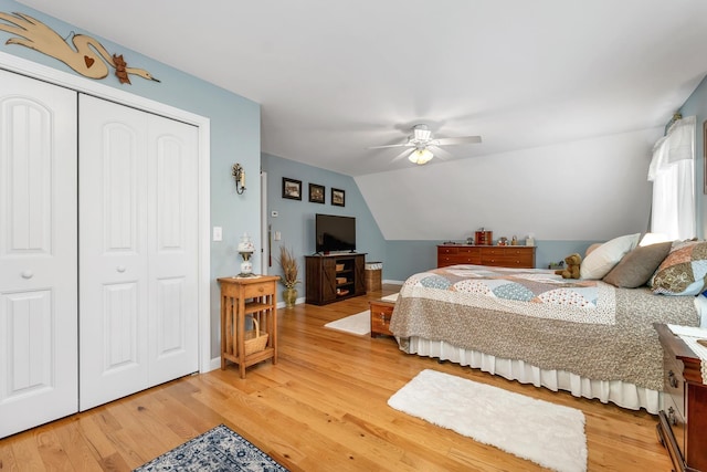 bedroom with a closet, wood finished floors, lofted ceiling, baseboards, and a ceiling fan