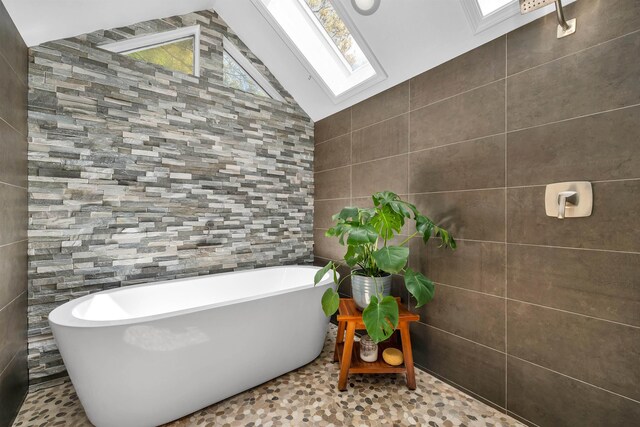 204 Chase Way, Manchester, NH 03104 - bathroom featuring tile walls, a freestanding bath, a skylight, and vaulted ceiling