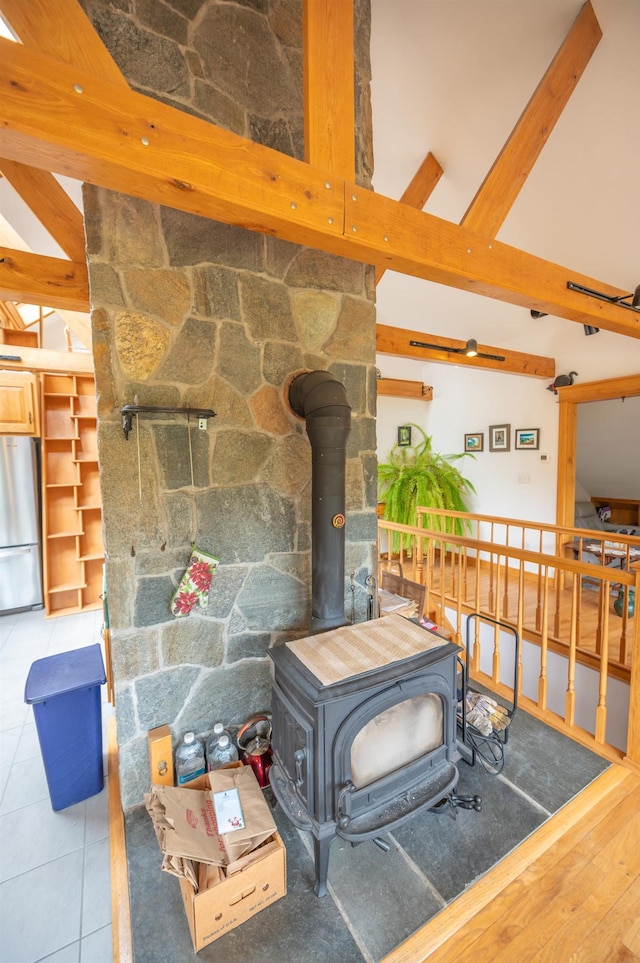 detailed view of freestanding refrigerator, a wood stove, and beam ceiling