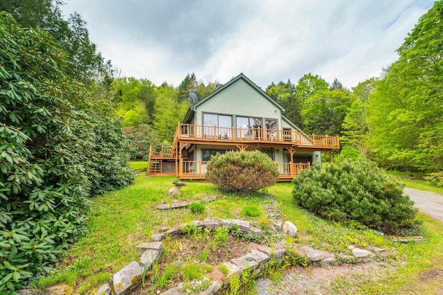 back of house featuring a deck, stairway, a forest view, and a yard