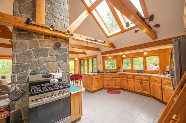 kitchen featuring stainless steel appliances, a skylight, beamed ceiling, light tile patterned floors, and healthy amount of natural light