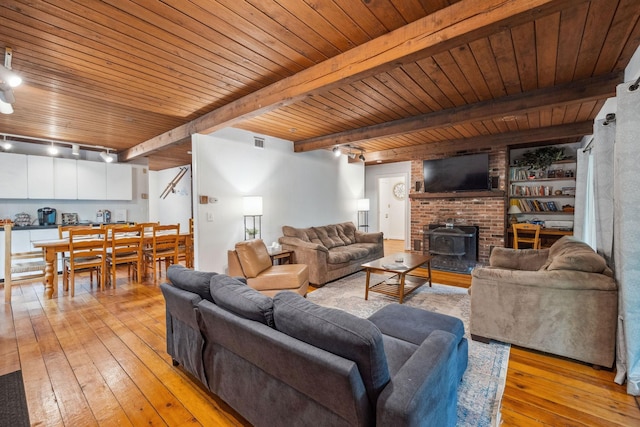 46 Crestwood Dr, Conway, NH 03860 - living room featuring light wood-type flooring, a wood stove, wooden ceiling, beam ceiling, and rail lighting