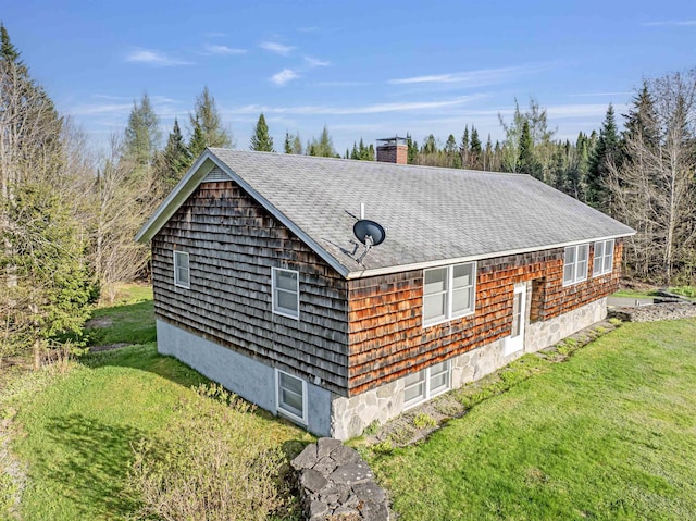 view of home's exterior with a shingled roof, a lawn, and a chimney