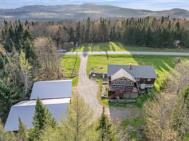 aerial view of property and surrounding area with a forest and a mountain backdrop