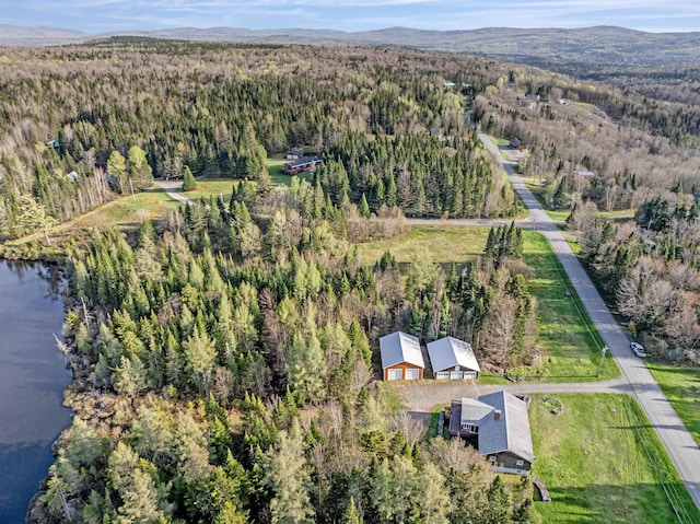 aerial view of property and surrounding area featuring a forest and a water and mountain view