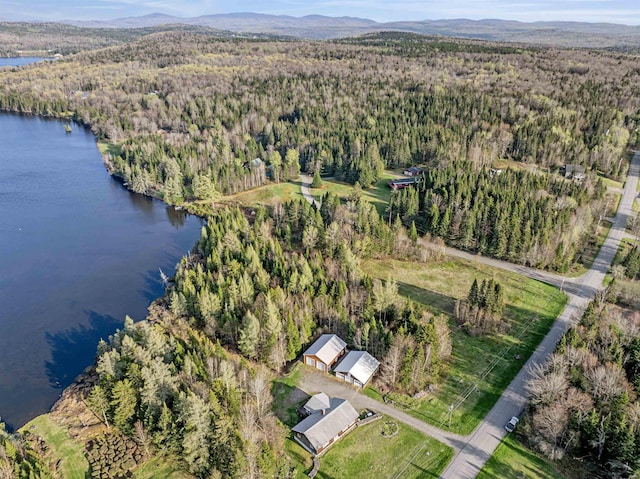 aerial view of property and surrounding area with a heavily wooded area and a water and mountain view