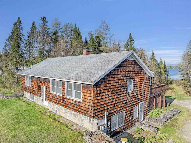 view of side of property featuring a shingled roof, a lawn, and a chimney