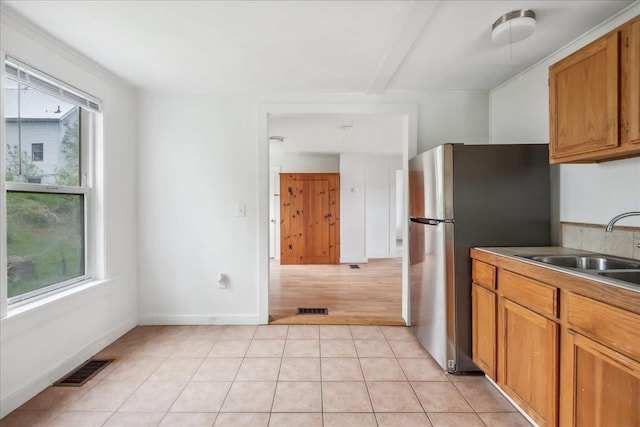 16 Shurtleff Pl, Barre City, VT 05641 - kitchen with a sink, freestanding refrigerator, light tile patterned floors, brown cabinets, and baseboards