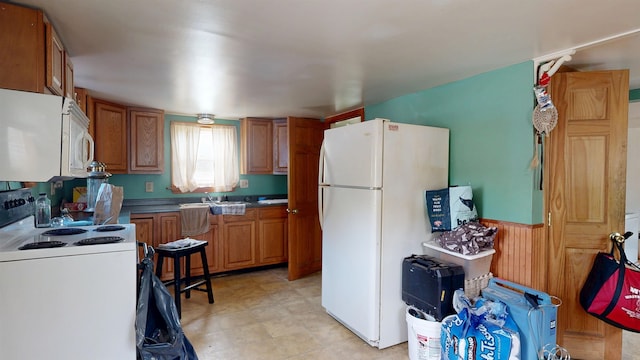 17 Convent Sq, Burlington, VT 05401 - kitchen with white appliances, brown cabinetry, a sink, a wainscoted wall, and wooden walls