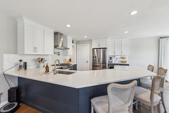 222 Standish Ln, Hudson, NH 03051 - kitchen with appliances with stainless steel finishes, wall chimney exhaust hood, backsplash, wood finished floors, and a peninsula