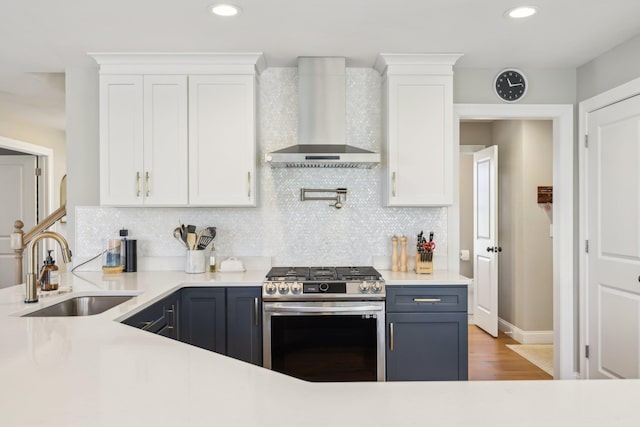 222 Standish Ln, Hudson, NH 03051 - kitchen with stainless steel gas range, wall chimney exhaust hood, a sink, white cabinets, and recessed lighting