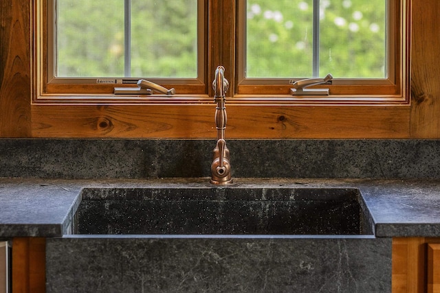 kitchen view of tasteful backsplash, a sink, brown cabinets, and dark countertops