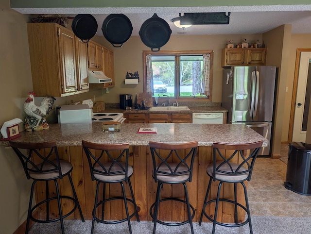 11 Cascade Dr Unit 288, Woodstock, NH 03262 - kitchen with white appliances, under cabinet range hood, a peninsula, a sink, and a kitchen bar