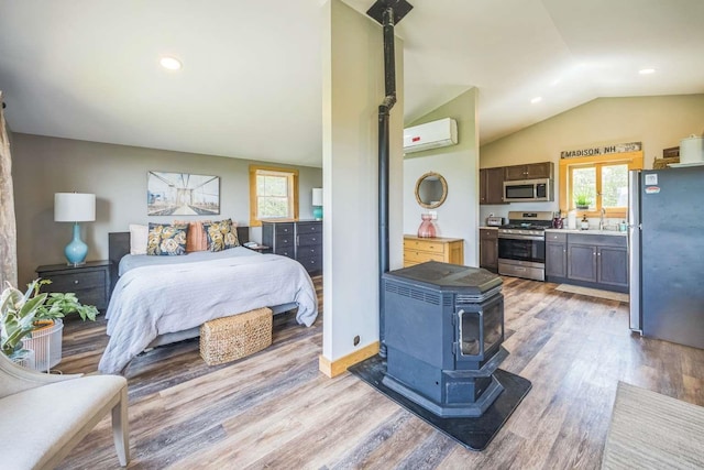 42 Peak Vista Ln, Madison, NH 03849 - bedroom with freestanding refrigerator, a wood stove, a wall unit AC, a sink, and vaulted ceiling