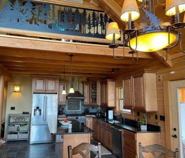 42 Peak Vista Ln, Madison, NH 03849 - kitchen featuring stainless steel appliances, wall chimney exhaust hood, dark countertops, a center island, and decorative light fixtures