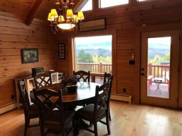 42 Peak Vista Ln, Madison, NH 03849 - dining space with wood walls, baseboard heating, a chandelier, light wood-type flooring, and plenty of natural light