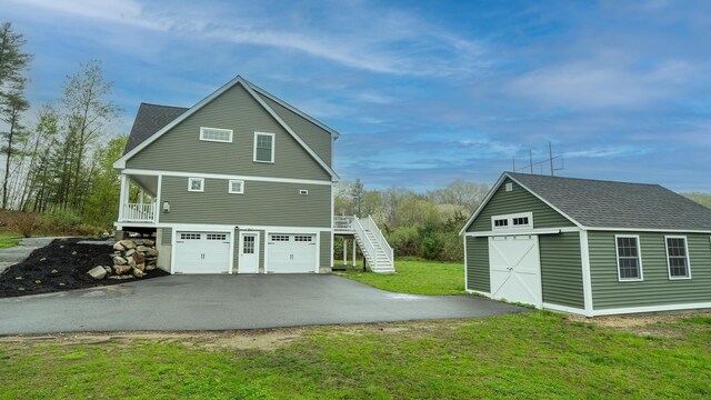21 Lovering Rd, North Hampton, NH 03862 - view of home's exterior with stairway, a lawn, an outbuilding, roof with shingles, and asphalt driveway