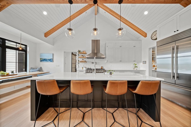 kitchen with built in fridge, wall chimney range hood, light wood-style floors, light countertops, and wooden ceiling