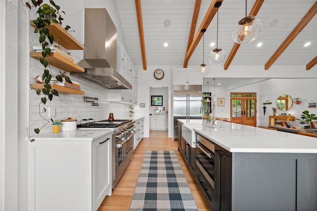 kitchen with high end appliances, wall chimney exhaust hood, light countertops, open shelves, and recessed lighting