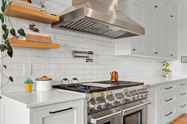 kitchen featuring range with two ovens, wall chimney range hood, open shelves, tasteful backsplash, and white cabinets