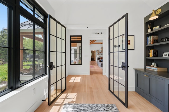 hall with french doors, light wood-style flooring, and baseboards