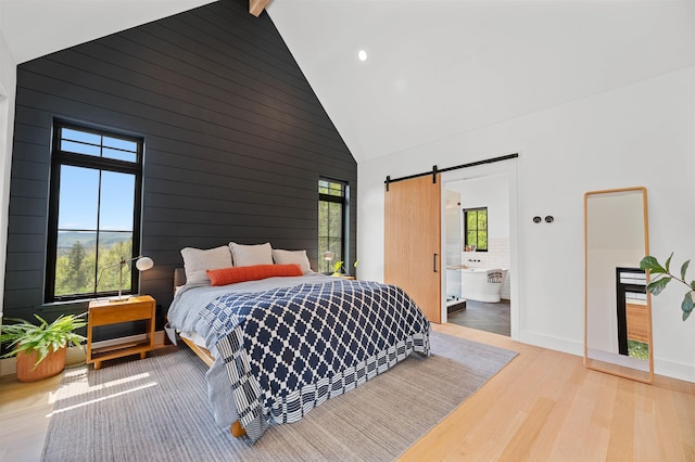 bedroom with high vaulted ceiling, wood finished floors, a barn door, baseboards, and recessed lighting