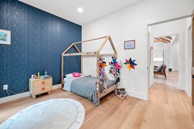 bedroom featuring wallpapered walls, wood finished floors, and baseboards